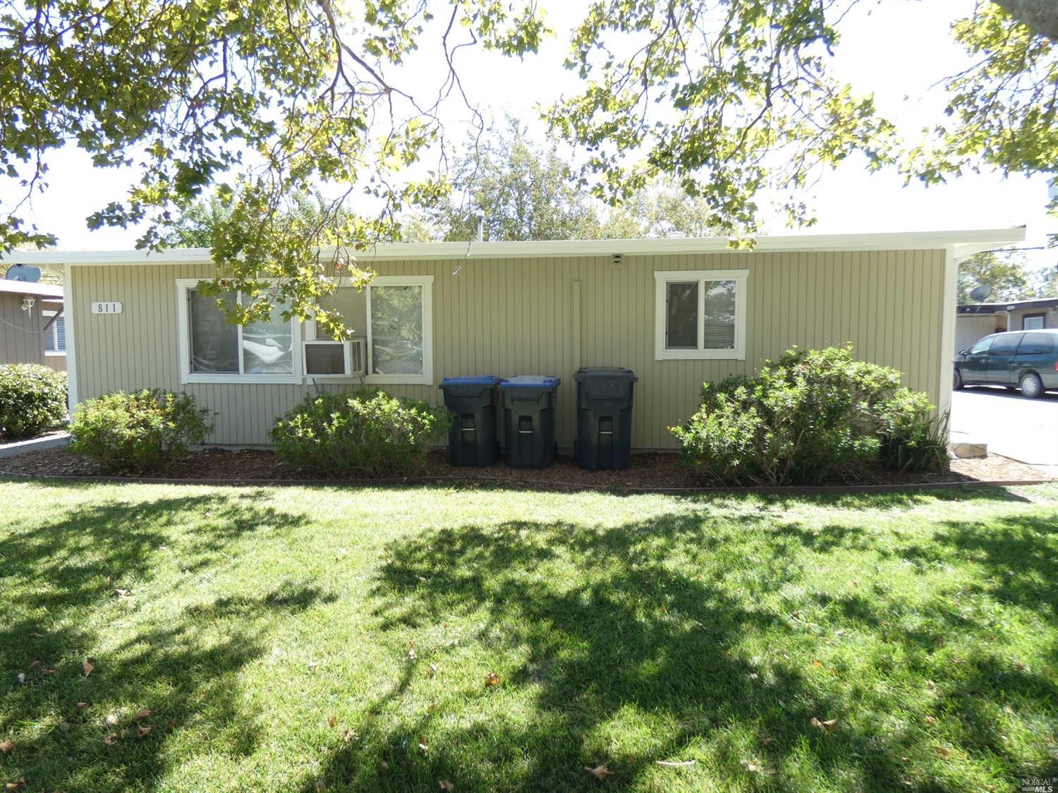 front view of a house with potted plants and a large tree