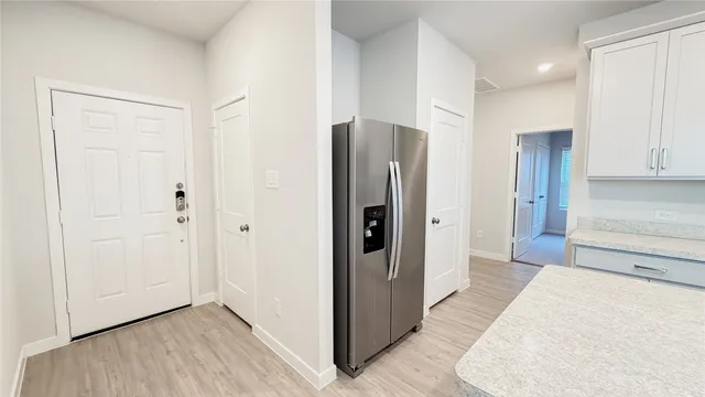 a view of a kitchen with wooden floor and a refrigerator