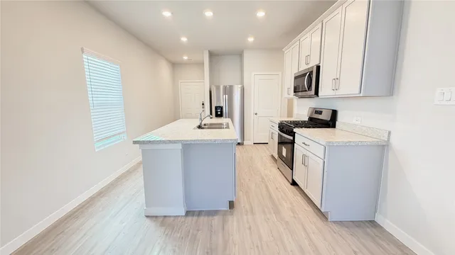 a kitchen with kitchen island granite countertop a sink and wooden floor
