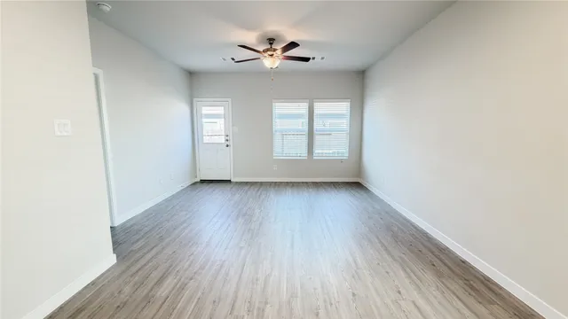 an empty room with wooden floor and windows