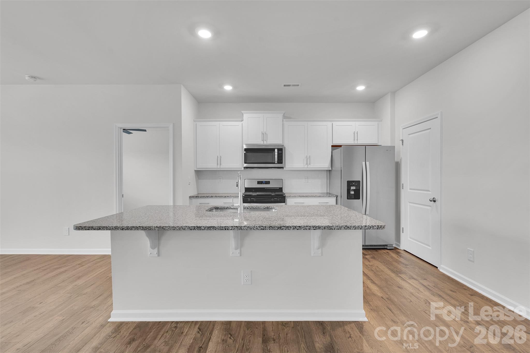 1917 Vanderlyn Street Monroe, NC 28112 - Photo 14 of 14 a large kitchen with stainless steel appliances granite countertop a stove a sink a refrigerator and white cabinets with wooden floor