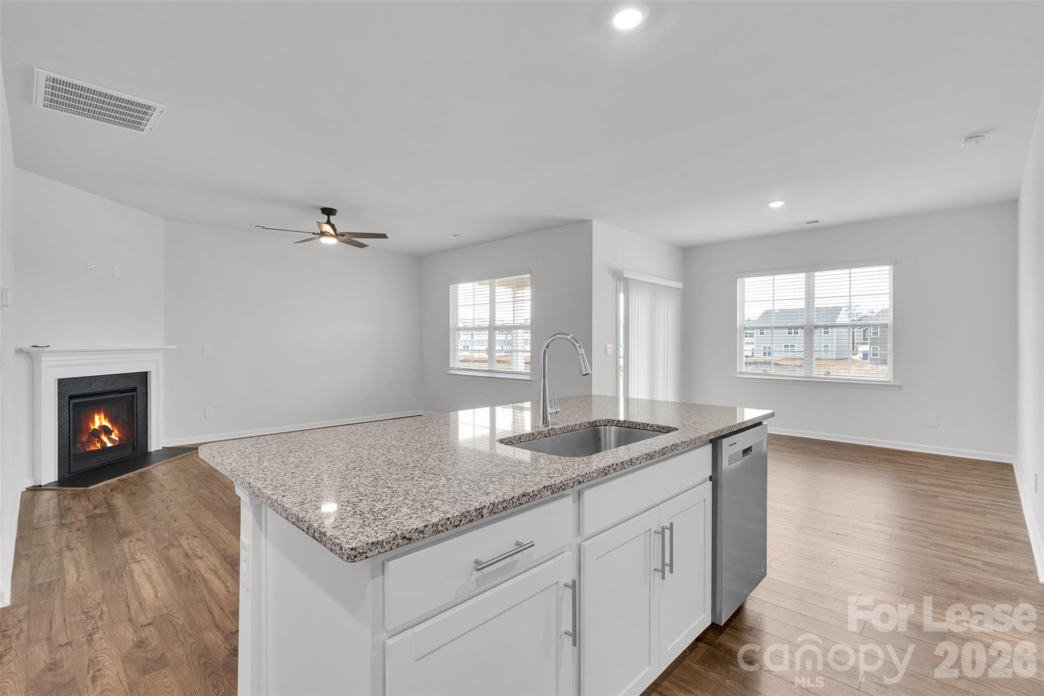 1917 Vanderlyn Street Monroe, NC 28112 - Photo 8 of 14 a hall with kitchen island a sink dishwasher a fireplace with wooden floor and chandelier