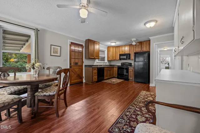 a kitchen with stainless steel appliances kitchen island granite countertop a refrigerator a stove a microwave oven a dining table and chairs with wooden floor