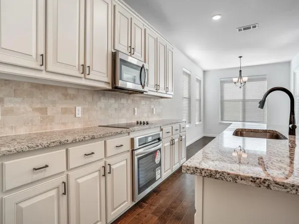 a kitchen with granite countertop a sink stainless steel appliances and white cabinets