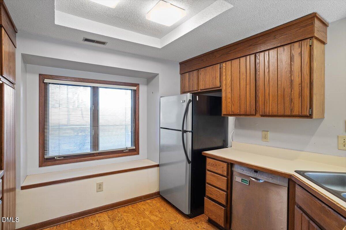 4329 Southwind Drive Raleigh, NC 27613 - Photo 15 of 30 a kitchen with stainless steel appliances granite countertop a refrigerator a sink dishwasher and cabinets with wooden floor