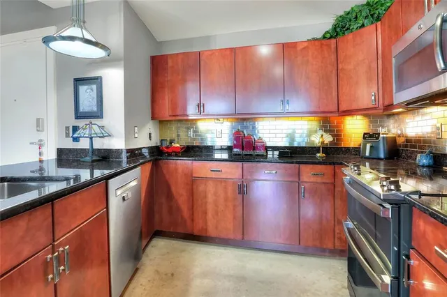 a kitchen with stainless steel appliances granite countertop wooden cabinets a stove top oven a sink and dishwasher
