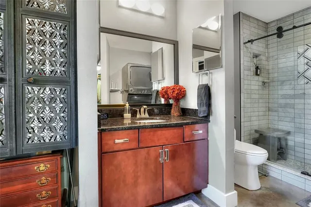 a bathroom with a granite countertop sink a toilet and shower