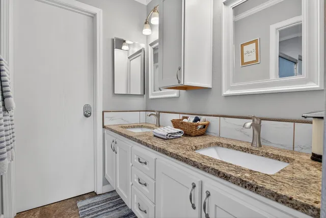 a bathroom with a granite countertop double vanity sink and mirror