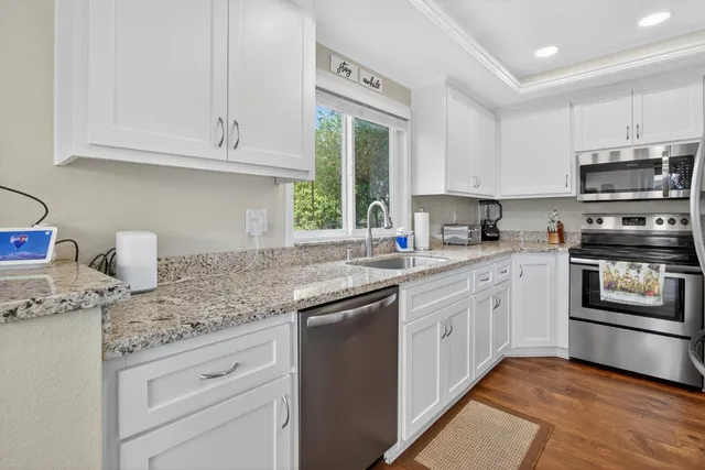 a kitchen with granite countertop white cabinets and stainless steel appliances