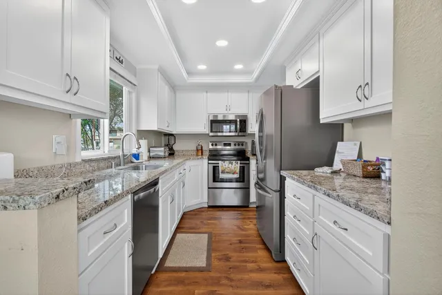 a kitchen with granite countertop kitchen island white cabinets stainless steel appliances and a counter space
