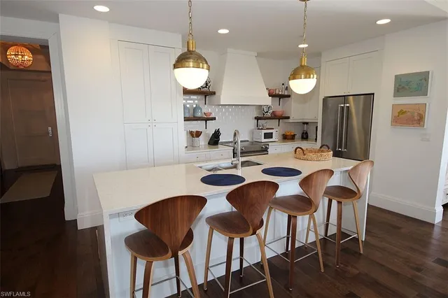 a large living room with stainless steel appliances kitchen island granite countertop furniture and a chandelier