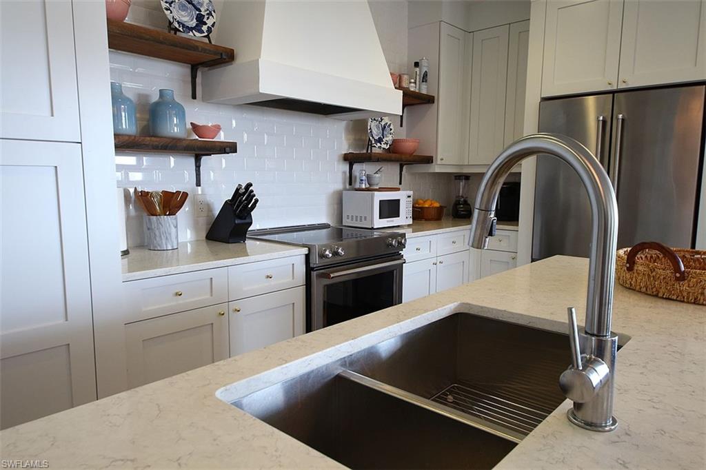 1035 3rd Avenue South, Unit 411 Naples, FL 34102 - Photo 14 of 49 a kitchen with stainless steel appliances a stove a sink and a refrigerator