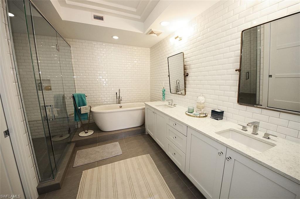 1035 3rd Avenue South, Unit 411 Naples, FL 34102 - Photo 17 of 49 a bathroom with a double vanity sink a mirror and a bathtub