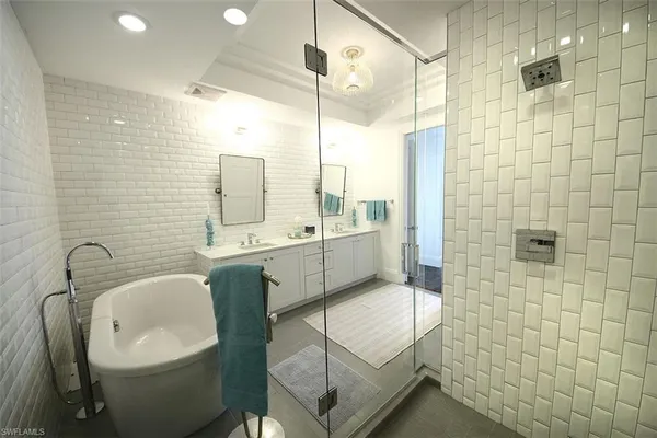 a bathroom with a double vanity sink a mirror and a bathtub