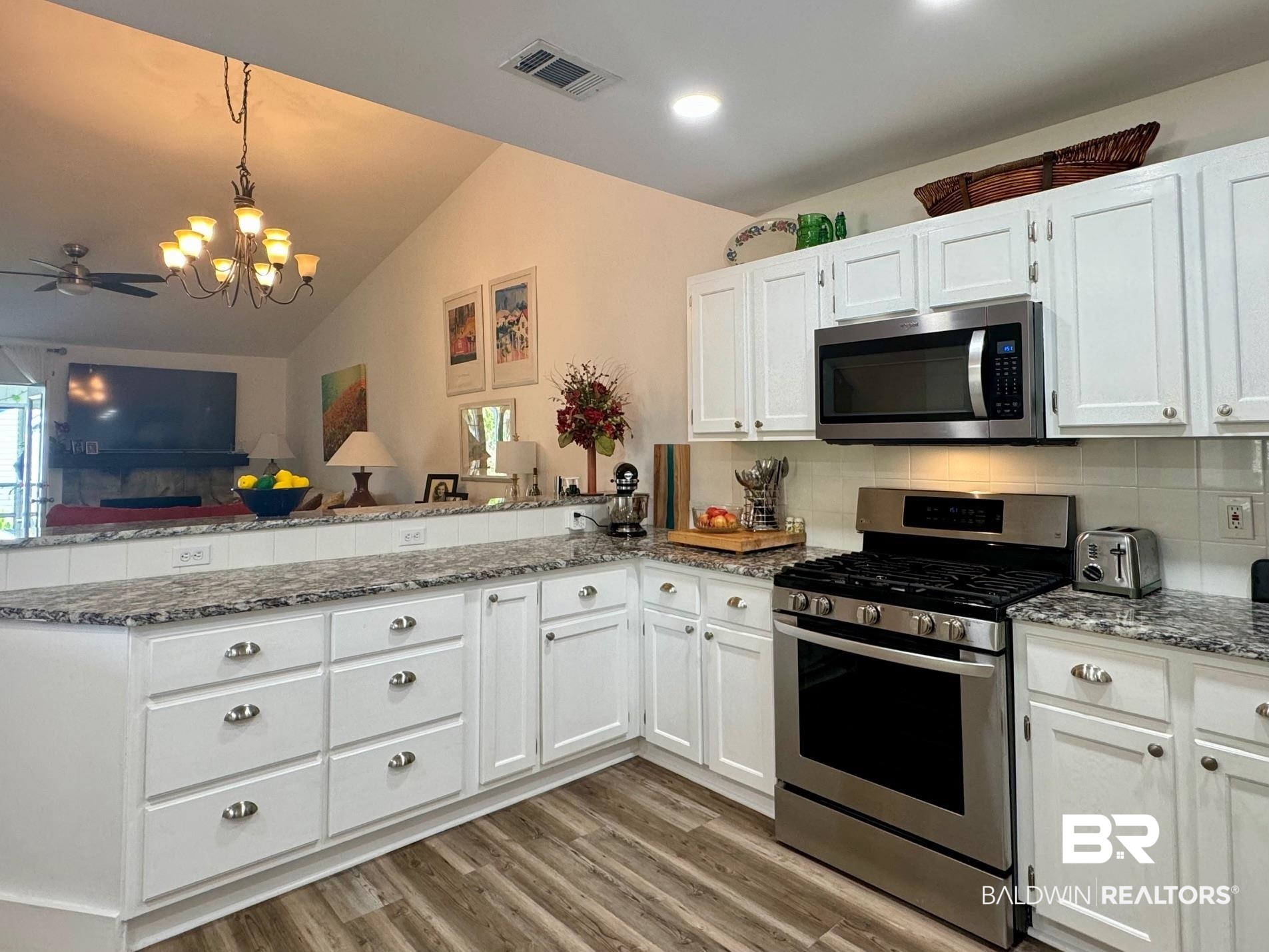 3200 Loop Road, Unit 55 Orange Beach, AL 36561 - Photo 9 of 40 Kitchen featuring lofted ceiling, decorative backsplash, stainless steel appliances, white cabinets, and kitchen peninsula