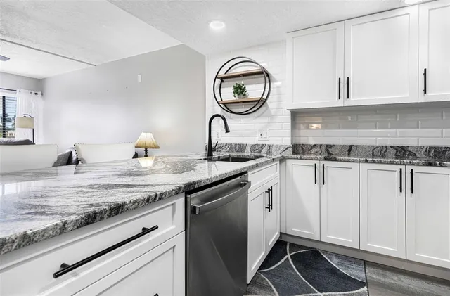 a kitchen with granite countertop white cabinets and a sink