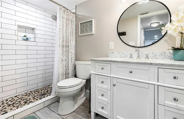 a bathroom with a granite countertop toilet sink and mirror