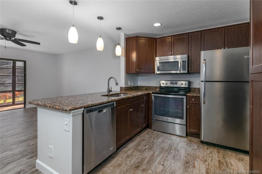 a kitchen with kitchen island granite countertop stainless steel appliances and wooden cabinets