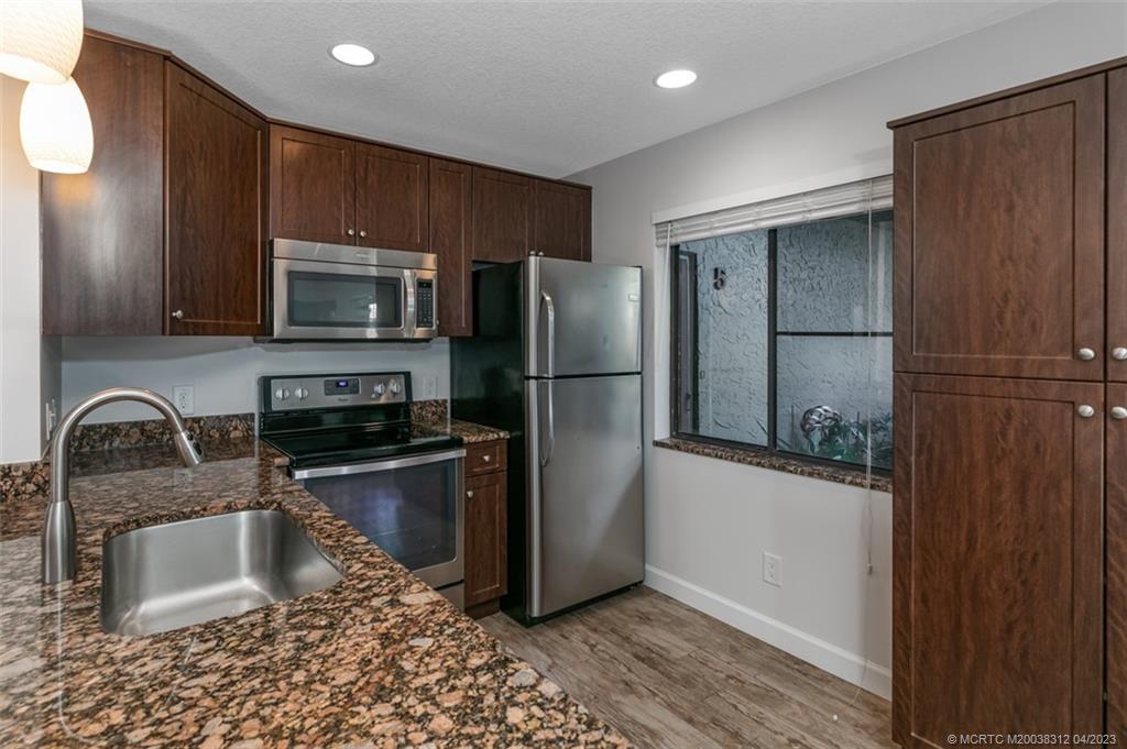 800 Northwest Fork Road, Unit 86 Stuart, FL 34994 - Photo 9 of 40 a kitchen with granite countertop a refrigerator and a sink