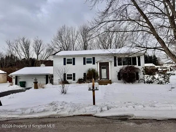 a front view of a house with a yard covered in snow