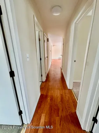 a view of a hallway with wooden floor and staircase