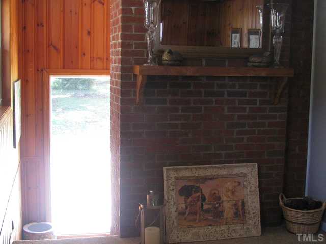 611 Crosby Road Durham, NC 27704 - Photo 11 of 25 Den with new Frieze carpet in a neutral color. No fireplace, but there was previously a wood-burning stove in the area under the mantle. The flue/chimney connection is behind the mirror. Sunny area at bottom of steps is perfect for plants.