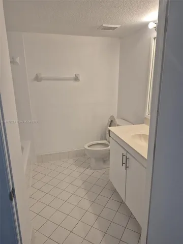 a bathroom with a granite countertop toilet and a sink
