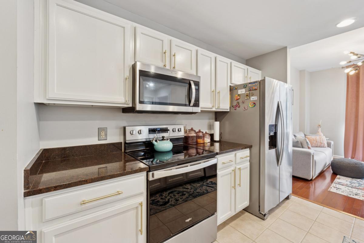 3040 Peachtree Road Northwest, Unit 702 Atlanta, GA 30305 - Photo 15 of 26 a kitchen with granite countertop a refrigerator stove and microwave