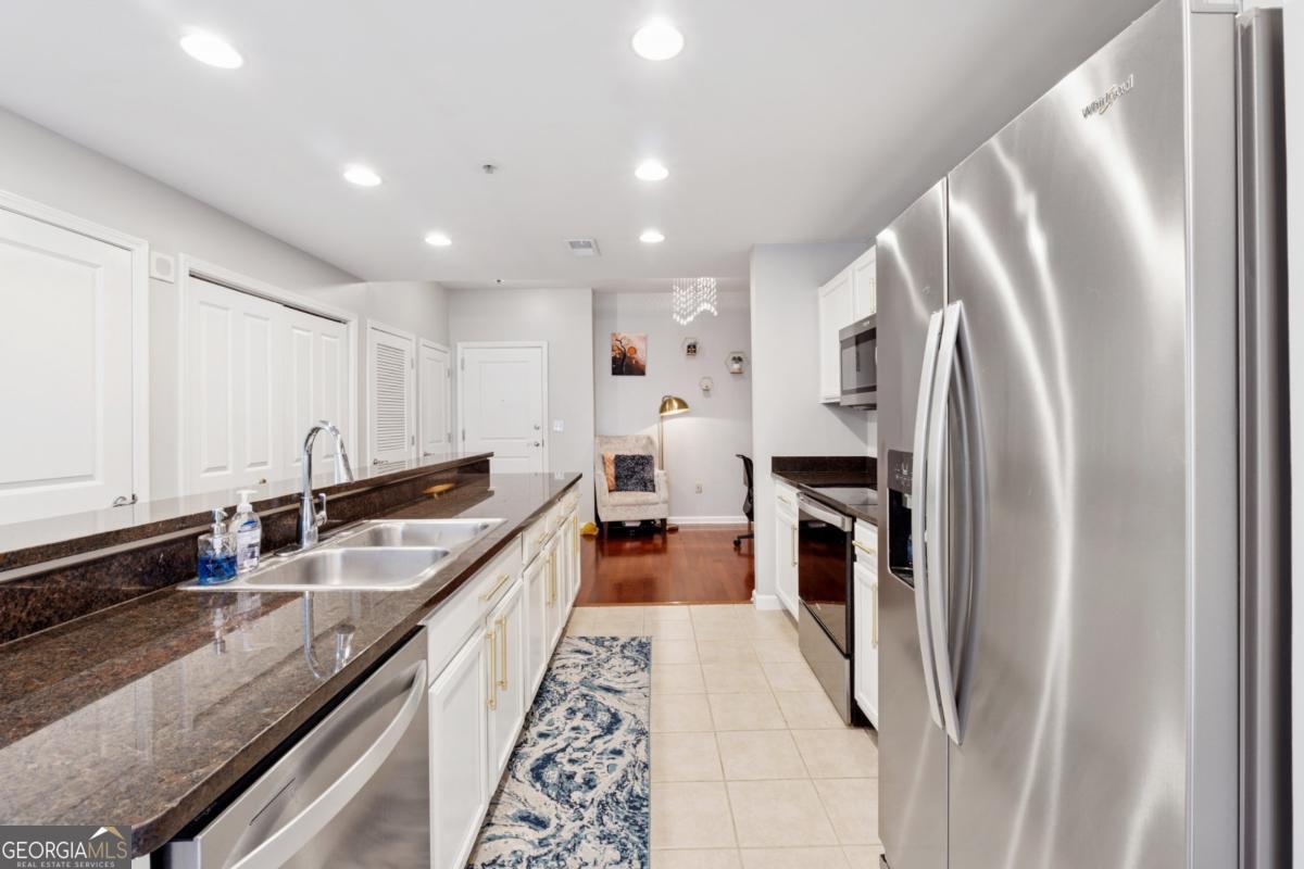 3040 Peachtree Road Northwest, Unit 702 Atlanta, GA 30305 - Photo 18 of 26 a large kitchen with stainless steel appliances granite countertop a refrigerator and a sink