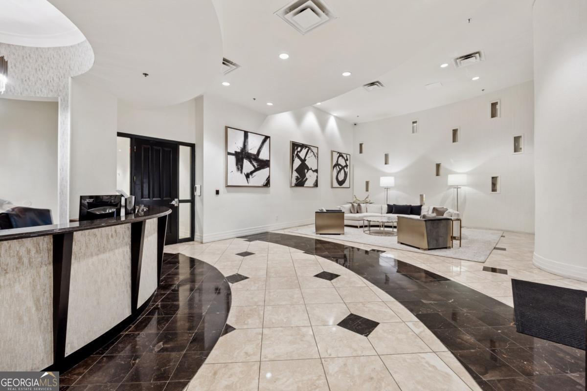 3040 Peachtree Road Northwest, Unit 702 Atlanta, GA 30305 - Photo 10 of 26 a large white kitchen with stainless steel appliances kitchen island granite countertop a refrigerator and a sink
