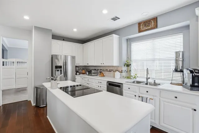 a kitchen with a sink a stove a refrigerator and white cabinets