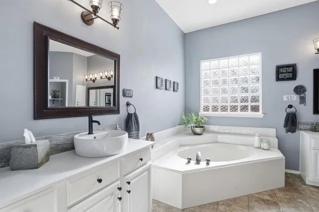 a bathroom with a tub a sink and mirror