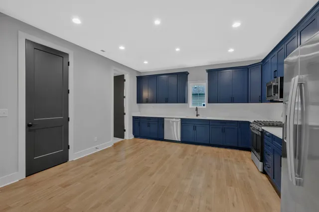 a large kitchen with stainless steel appliances granite countertop a refrigerator and a sink