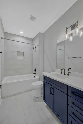 a bathroom with a bathtub shower sink vanity mirror and toilet