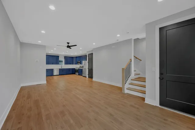 a view of empty room with wooden floor and kitchen