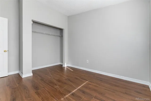 a view of an empty room with wooden floor and closet