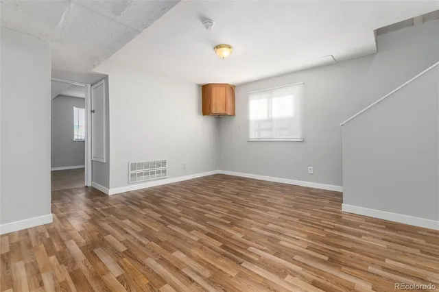 a view of empty room with wooden floor and fan