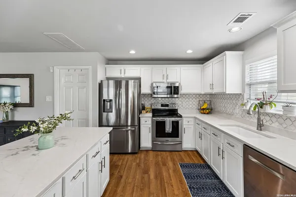 a kitchen with stainless steel appliances a sink dishwasher a refrigerator a stove top oven with wooden floor
