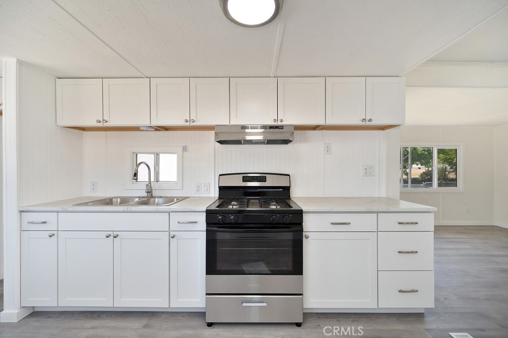 26455 Paradise Valley Road, Unit 86 Warner Springs, CA 92086 - Photo 13 of 34 a kitchen with white cabinets and a stove with wooden floor