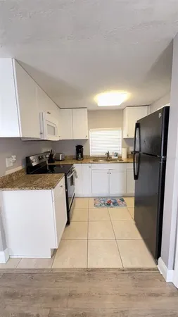 a kitchen with granite countertop a refrigerator and a stove top oven