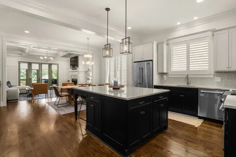 a kitchen with stainless steel appliances granite countertop a sink a stove a refrigerator and island with wooden floor