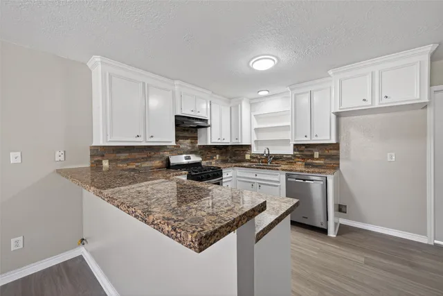 a kitchen with a refrigerator a stove a sink and white cabinets