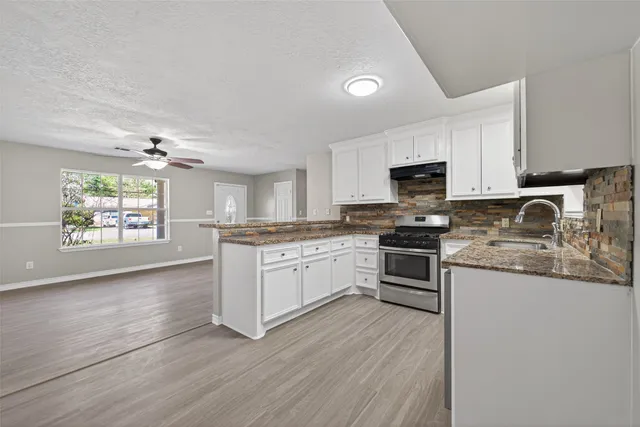 a kitchen with granite countertop a stove top oven a sink dishwasher and a refrigerator with wooden floor