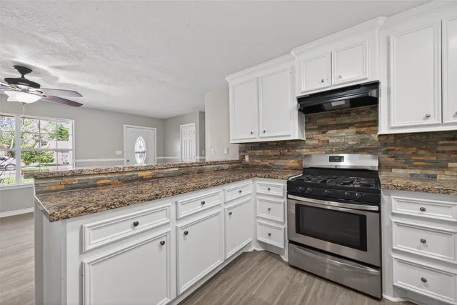 a kitchen with granite countertop white cabinets and appliances