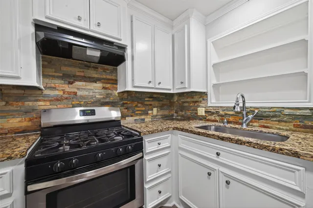 a kitchen with stainless steel appliances granite countertop white cabinets and black stove top oven with granite countertops