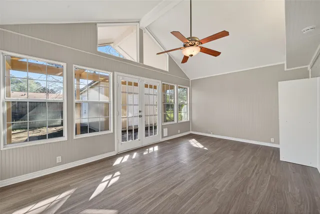 a view of an empty room with wooden floor and a window