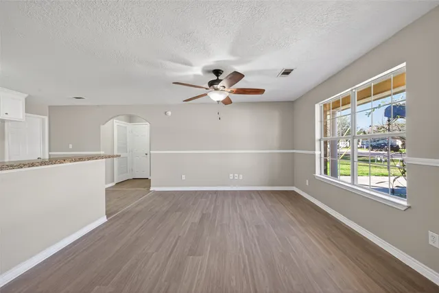 a view of an empty room with a window and wooden floor