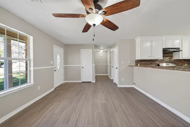 a view of an empty room with wooden floor and a window