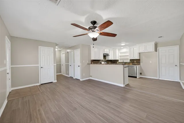 a view of a kitchen with a refrigerator a ceiling fan and wooden floor