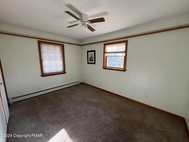 an empty room with windows and ceiling fan
